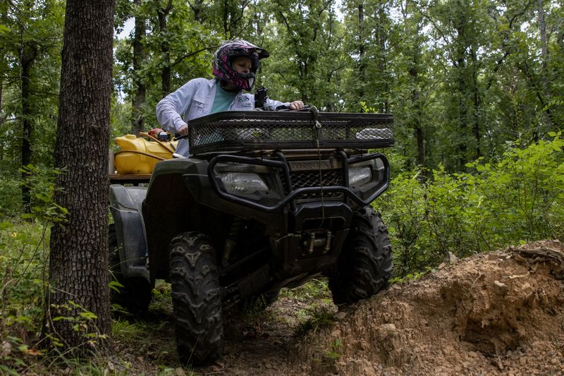 An ATV climbs over a dirt bank between trees