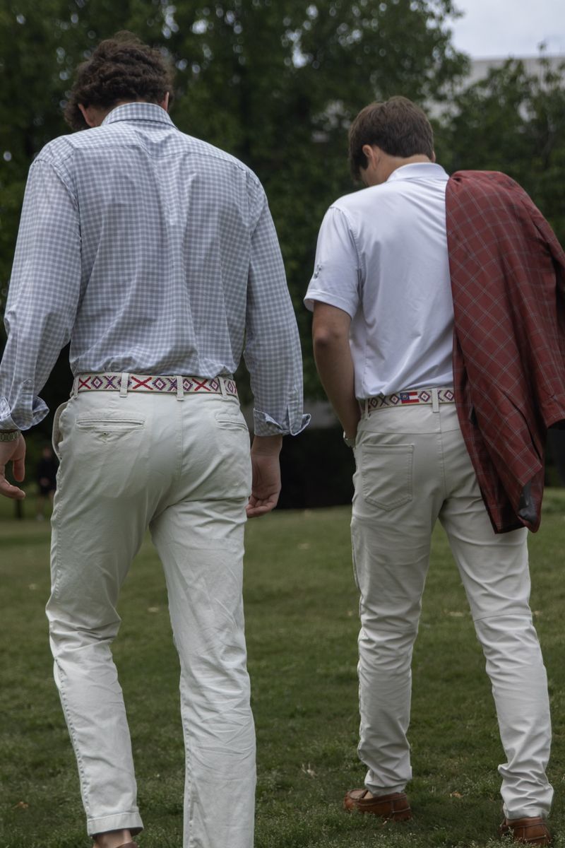 Two men in khakis and beaded belts seen from behind