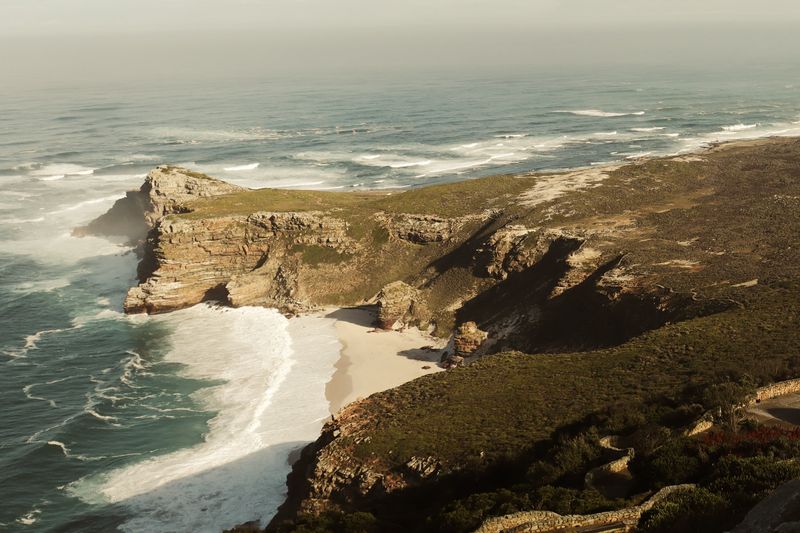 Ocean cliffs and a white sand cove from above
