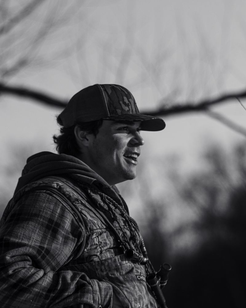 Black and white portrait of a smiling hunter in a ball cap