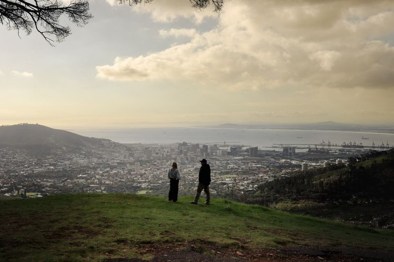 Two people on a hilltop overlooking a coastal city