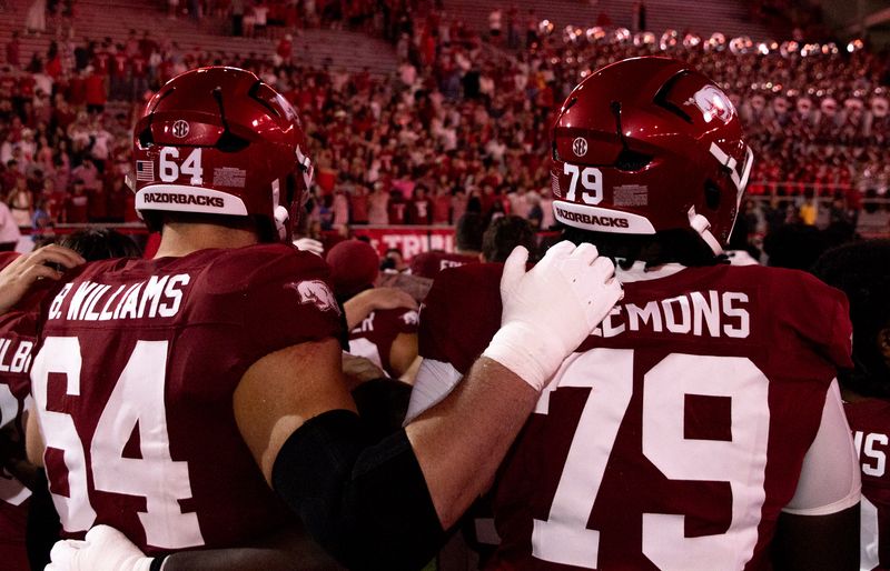 Razorback linemen 64 and 79 embrace after a game